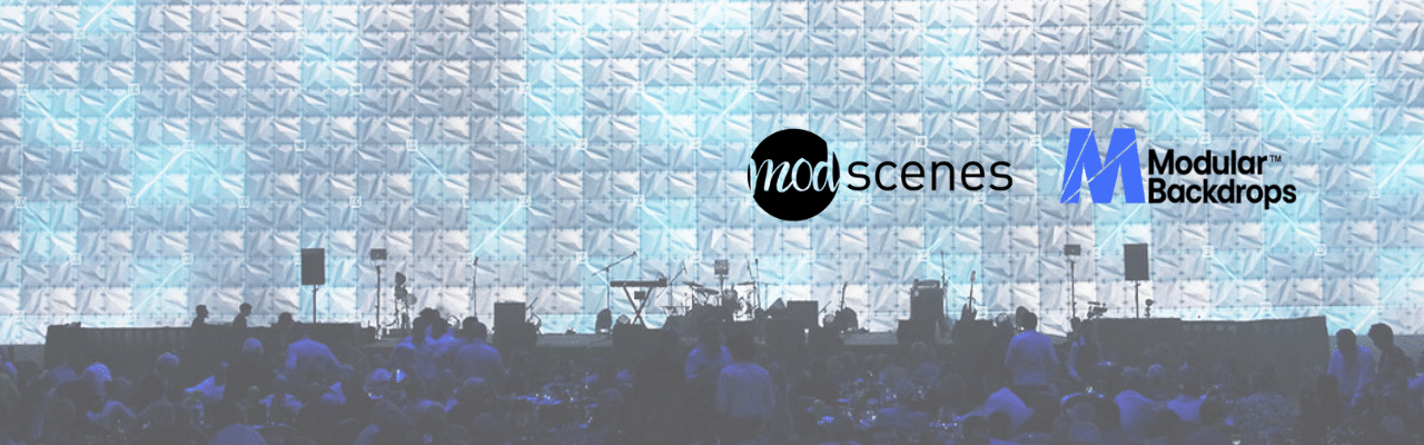 Audience seated in front of a large, illuminated event backdrop featuring geometric designs, with the Modscenes and Modular Backdrops logos displayed.